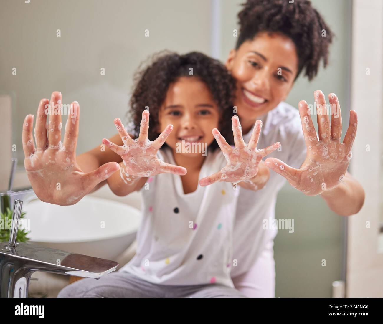 A mom teaching child to clean their hands, using soap and water in the bathroom to destroy germs to stay healthy. Kid washing dirty hand, keeps family Stock Photo