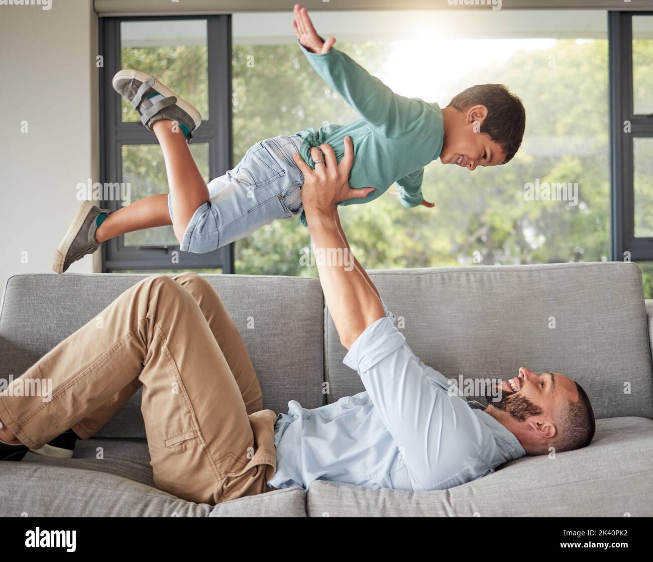 Relax, family and dad balance on sofa for fun bonding time together in cozy house in Mexico. Support, trust and love of Mexican father holding young Stock Photo
