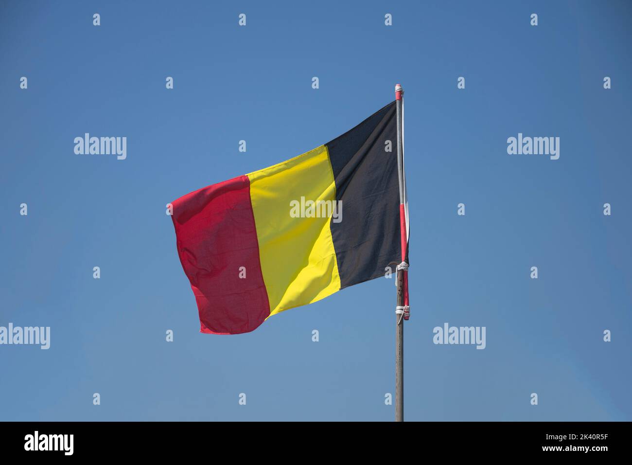 The Belgian flag or Belgian tricolor with a blue sky as background Stock Photo