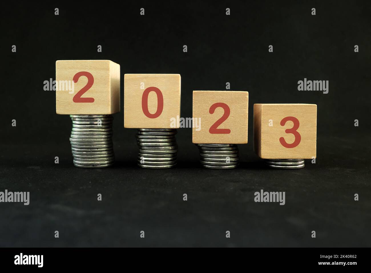 Year 2023 economic recession, financial crisis and bankruptcy concept. Decreasing stack of coins in dark black background. Stock Photo