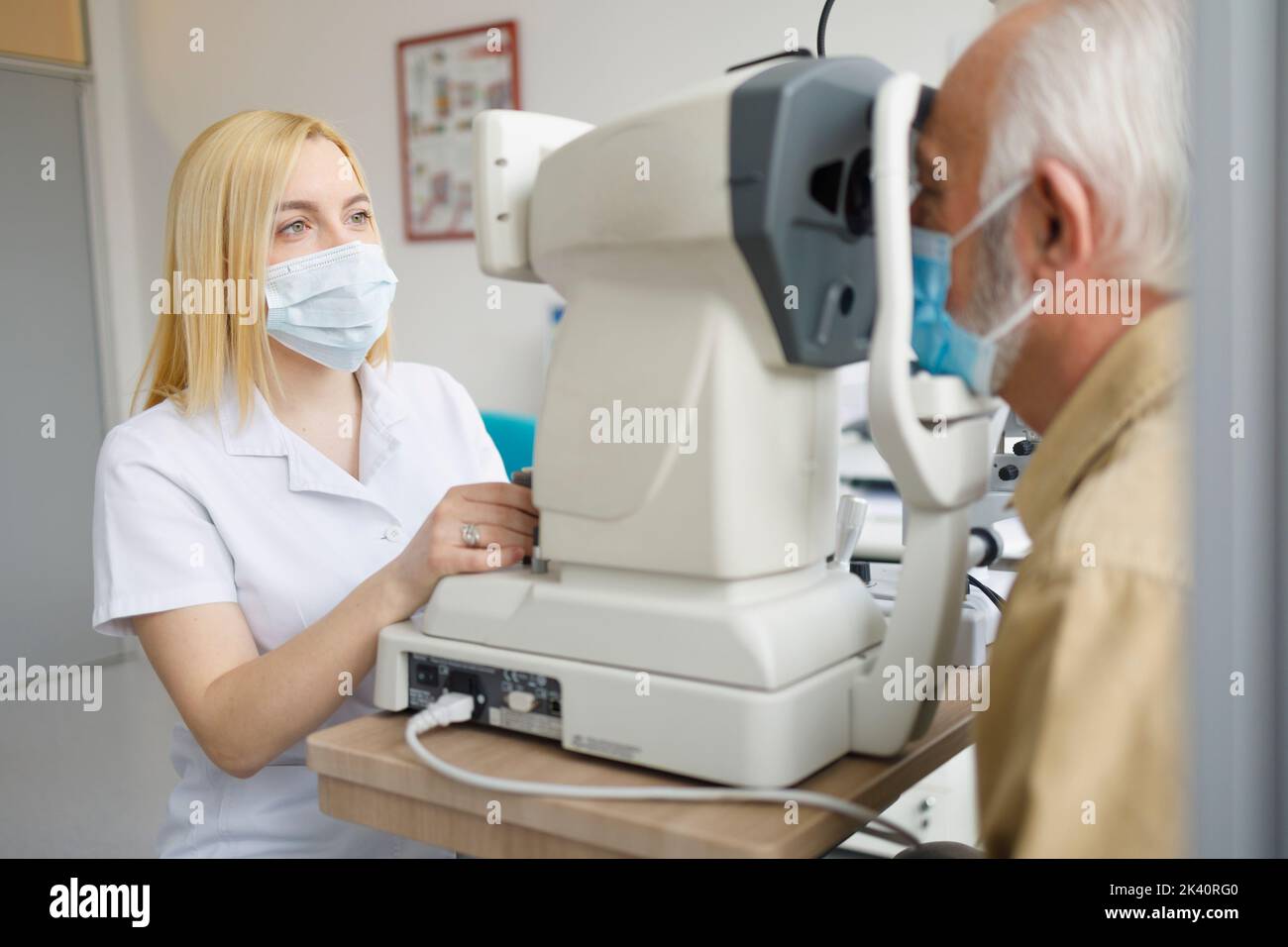 Female doctor looking at the patients eye with her ophthalmologist equipment Stock Photo