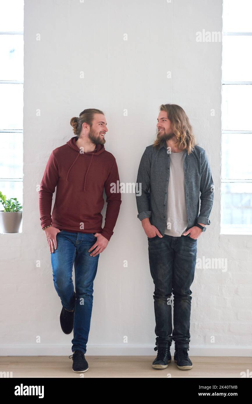 Family, smile and happy twins standing together with happiness in a home. Young smiling and identical male sibling people in a house by a wall showing Stock Photo