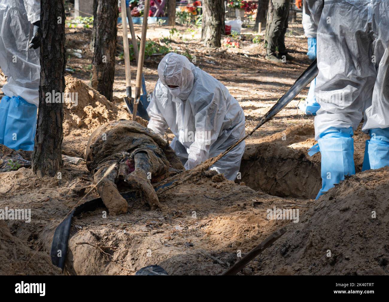 (EDITORS NOTE: Image depicts death)An investigator wearing protective gear is seen examining an exhumed body. A mass burial site was found in the outskirt of the eastern Ukrainian city, Izyum, Kharkiv region which has been liberated from Russian occupation two weeks ago. At least 445 new graves were found in the site of an existing cemetery while many only have numbers written on the wooden cross. All bodies will be exhumed and sent for forensic examination but it was told from initial investigations that some bodies shown sign of torture. (Photo by Ashley Chan / SOPA Images/Sipa USA) Stock Photo