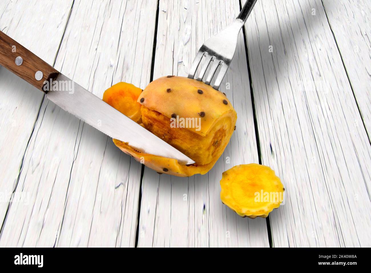 Peel prickly pears with fork and knife on white wooden table Stock Photo