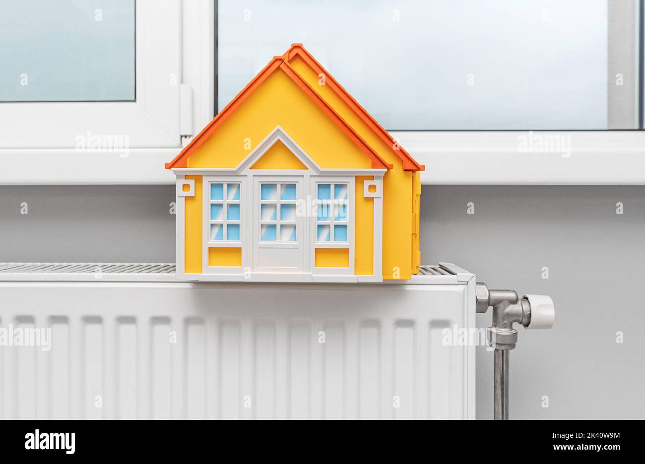 Model of a house on a radiator. Providing warmth during the cold season. Stock Photo