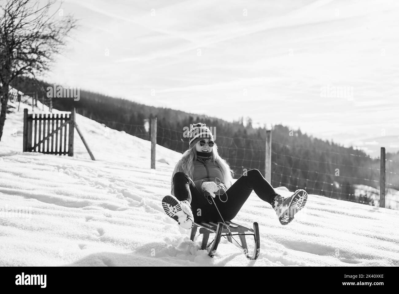Crazy girl speeding with vintage sledding on snow high mountain - Focus on face - Black and white editing Stock Photo
