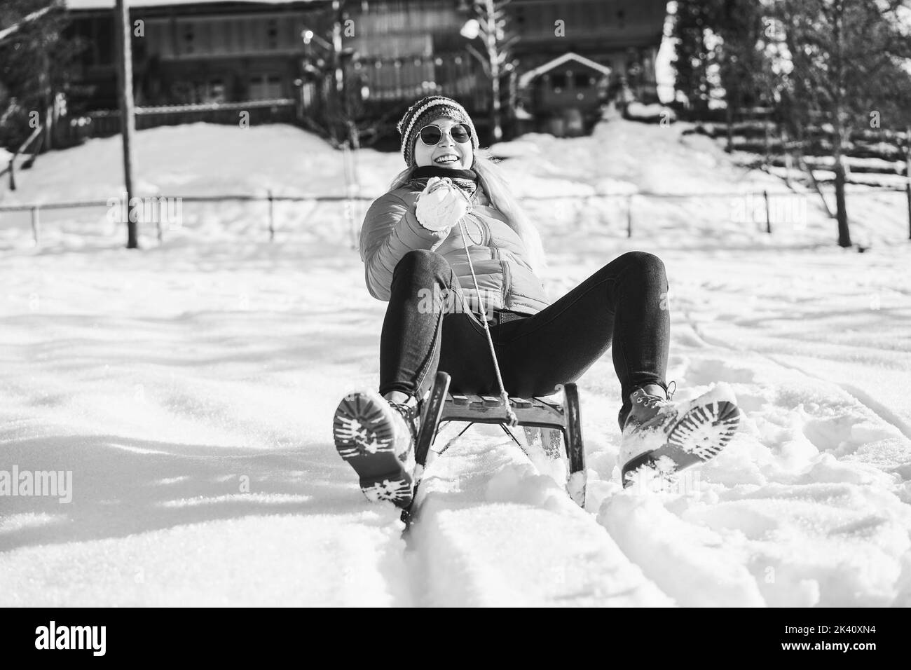 Crazy girl speeding with vintage sledding on snow high mountain - Focus on face - Black and white editing Stock Photo