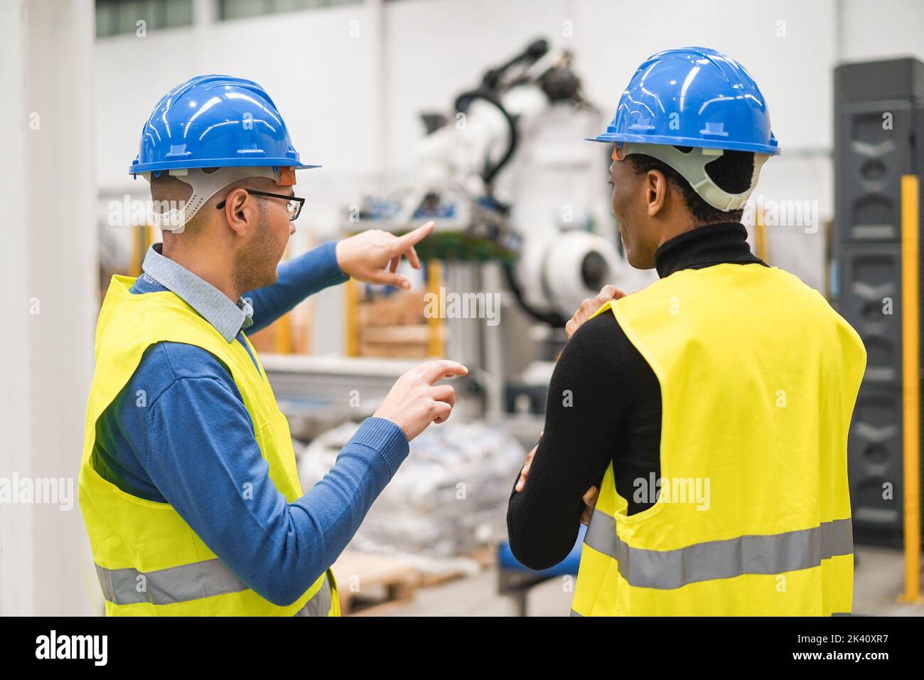 Multiethnic engineers working inside robotic factory - Focus on left man hardhat Stock Photo