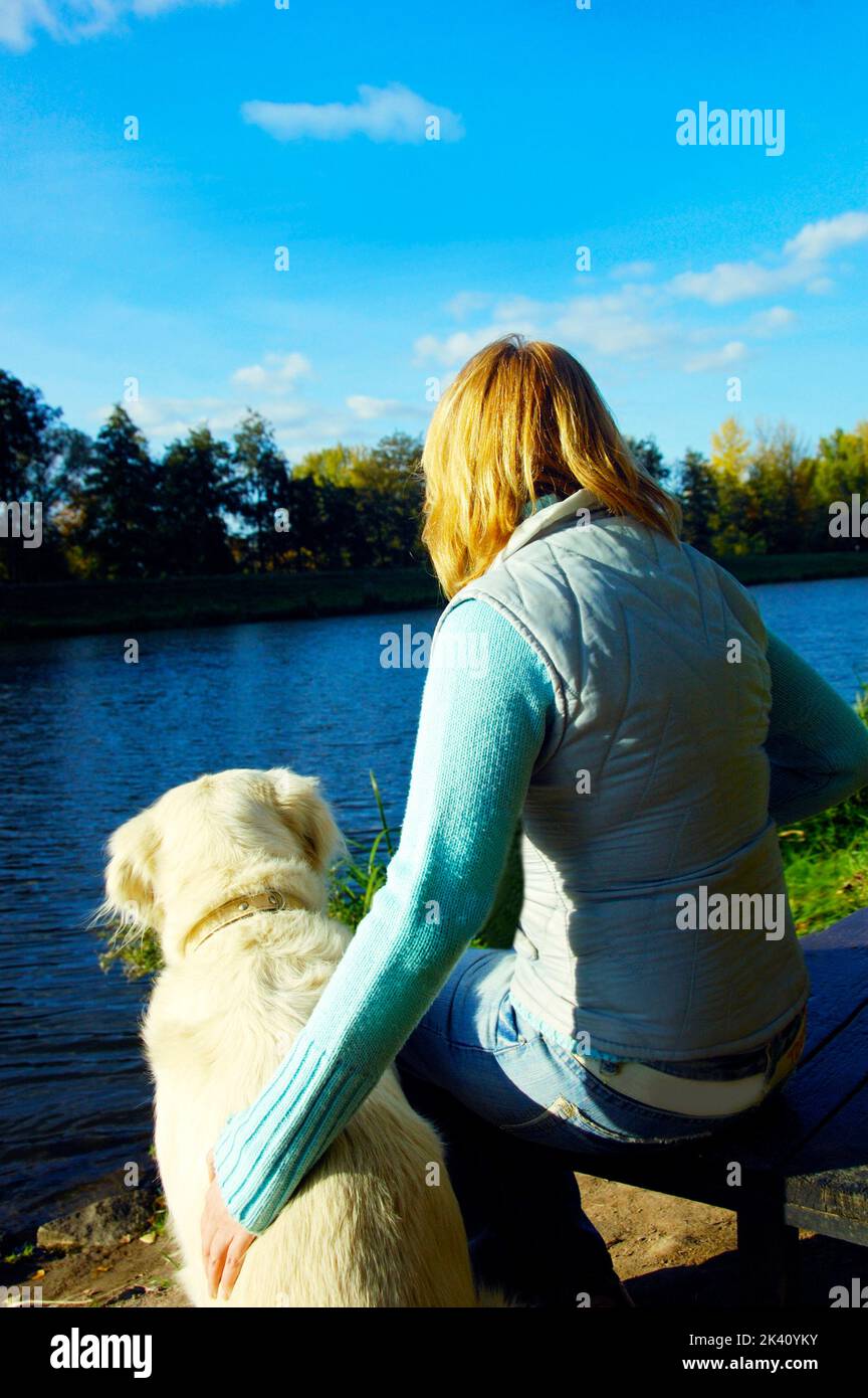 golden retriever dog with his owner on the bank of the river Stock Photo
