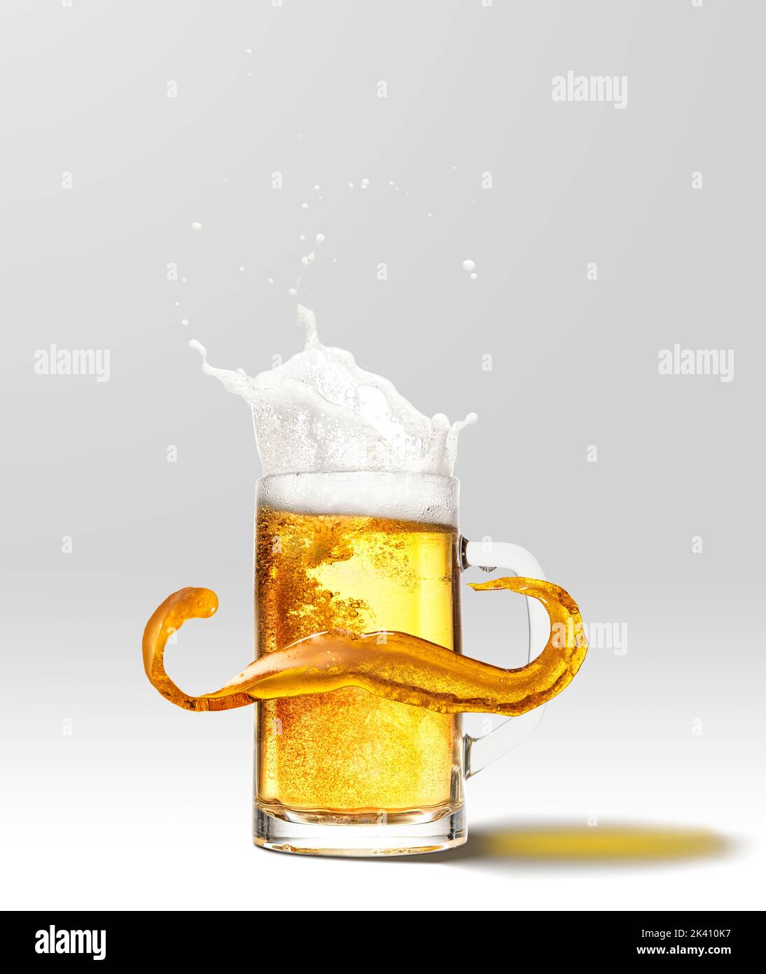 Foam splashes from full mug of frothy light lager beer isolated over light background. Concept of alcohol, oktoberfest, drinks, holidays and festivals Stock Photo