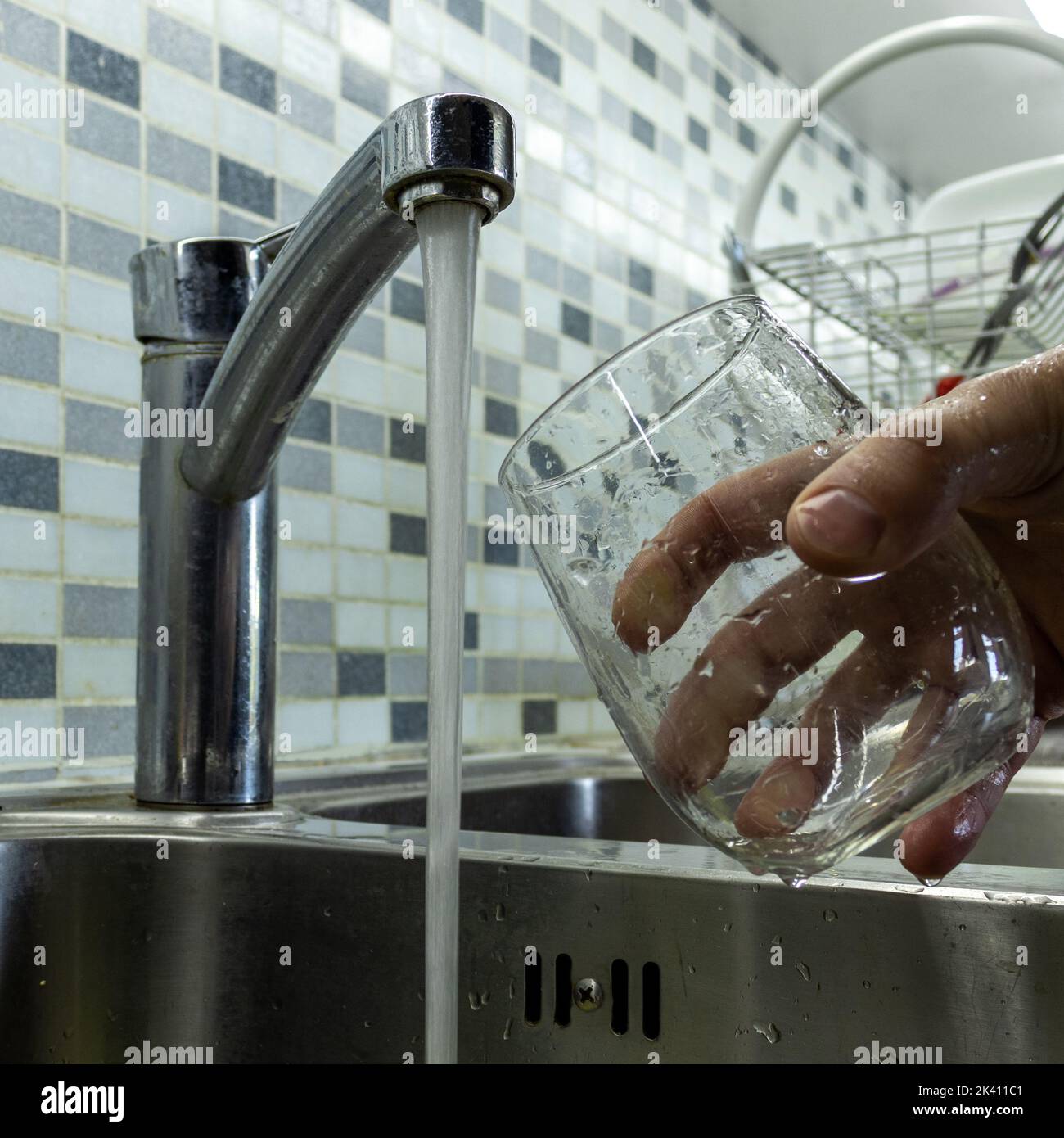 Caucasian man washing glasses in the kitchen. Hygiene Stock Photo