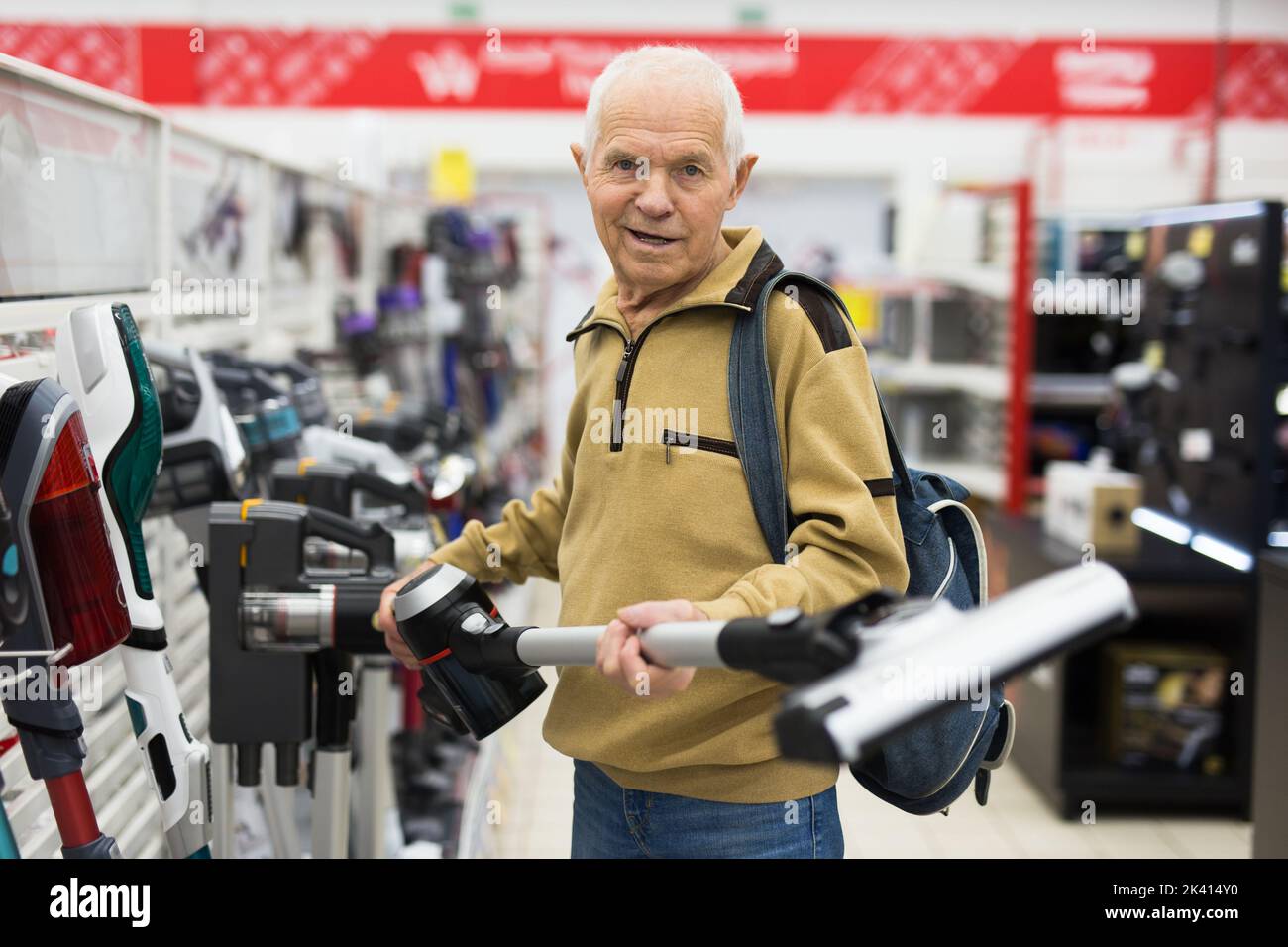 elderly man choosing Upright Vacuum hoover in showroom of electrical appliance store Stock Photo