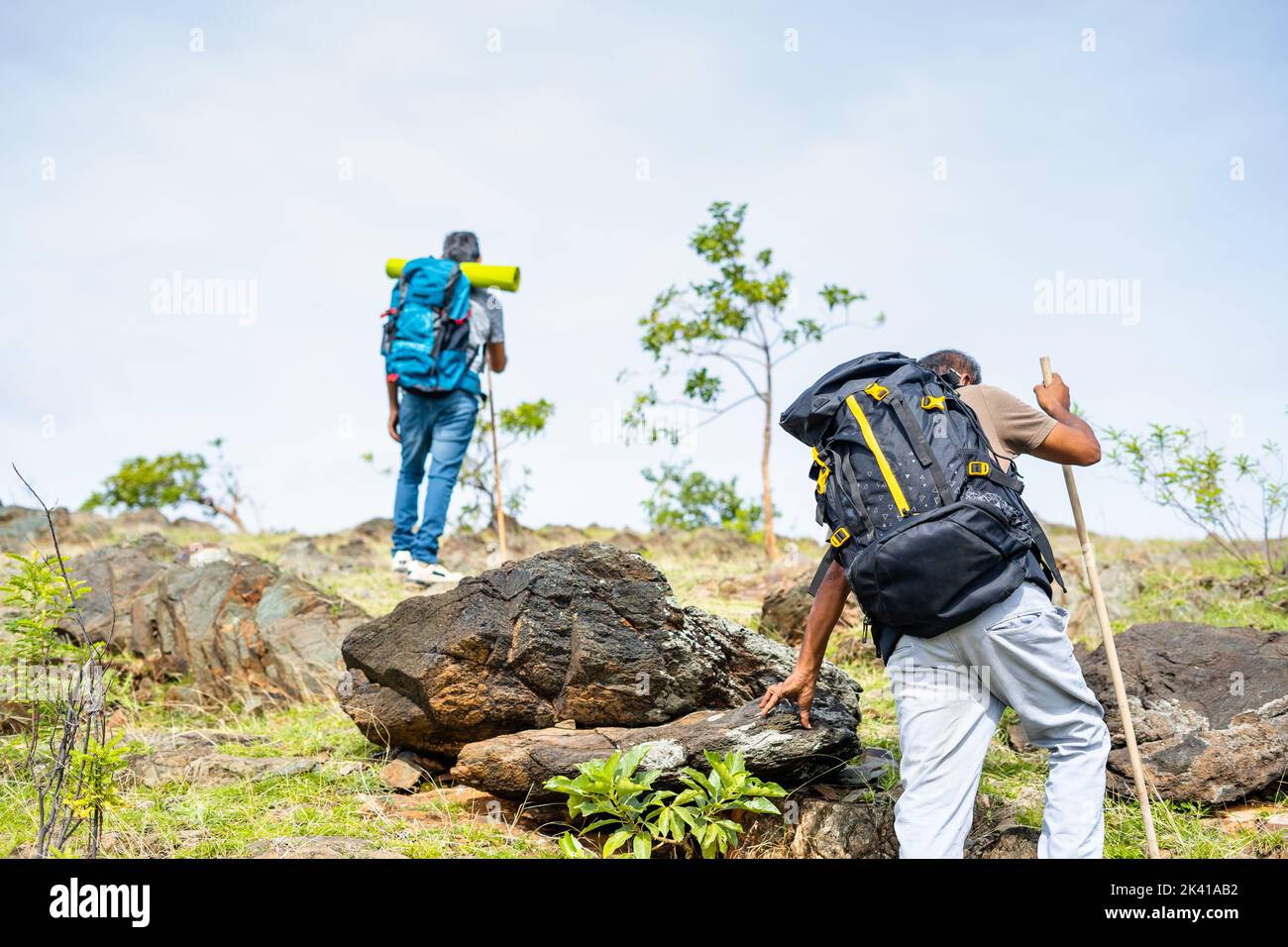 Back view tracking shot of middle aged hikers climbing hill or mountain - concept of adventure, leisure activities and trekking. Stock Photo