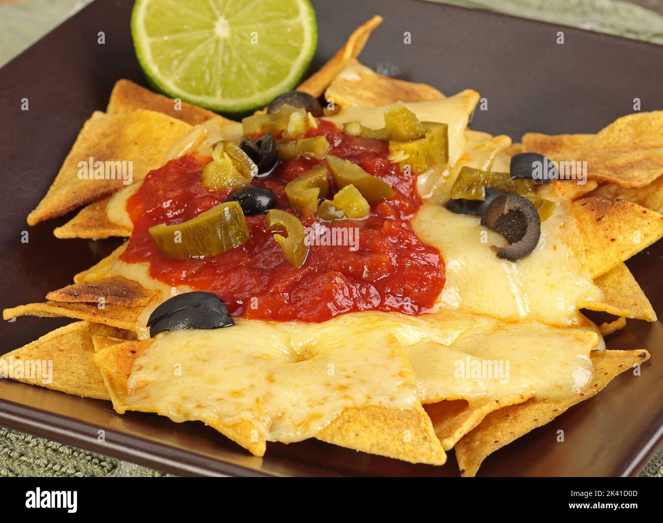 crisp cheesy nachos wit tomato salsa olives and jalapenos Stock Photo
