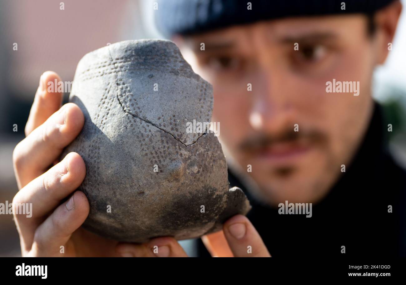 Memleben, Germany. 29th Sep, 2022. Tim Adam, a student of historic preservation, shows an engraving band vessel from 4500 BC that was found on the historic Memleben monastery grounds. Archaeologists have also determined the exact location of the former church of Emperor Otto II (955-983) on the site. In the 10th century, an imperial palace and a monastery stood in Memleben. The Memleben monastery was first mentioned in documents in 979. Credit: Hendrik Schmidt/dpa/Alamy Live News Stock Photo