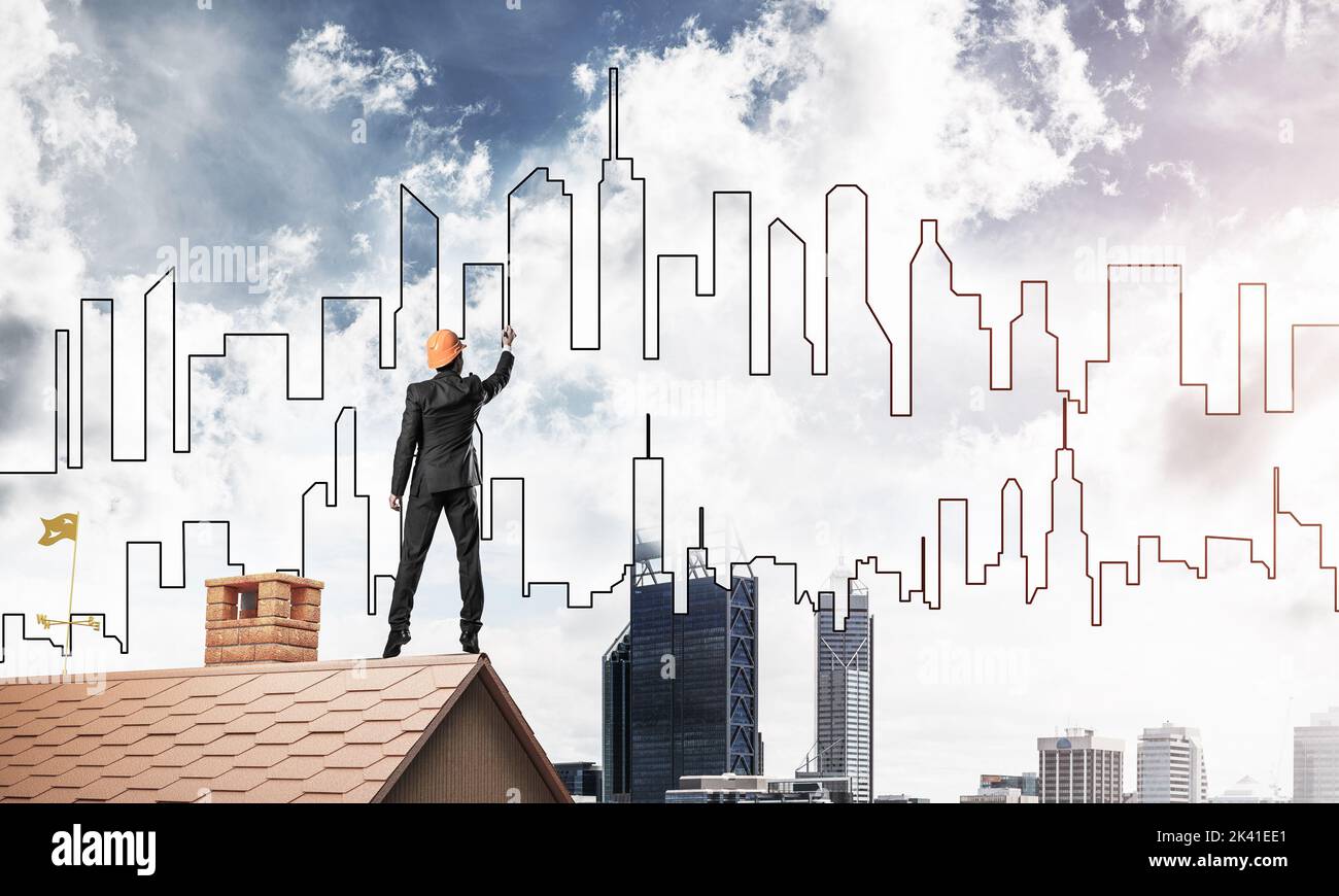 Man architect draw silhouette of modern city on blue sky. Mixed Stock Photo