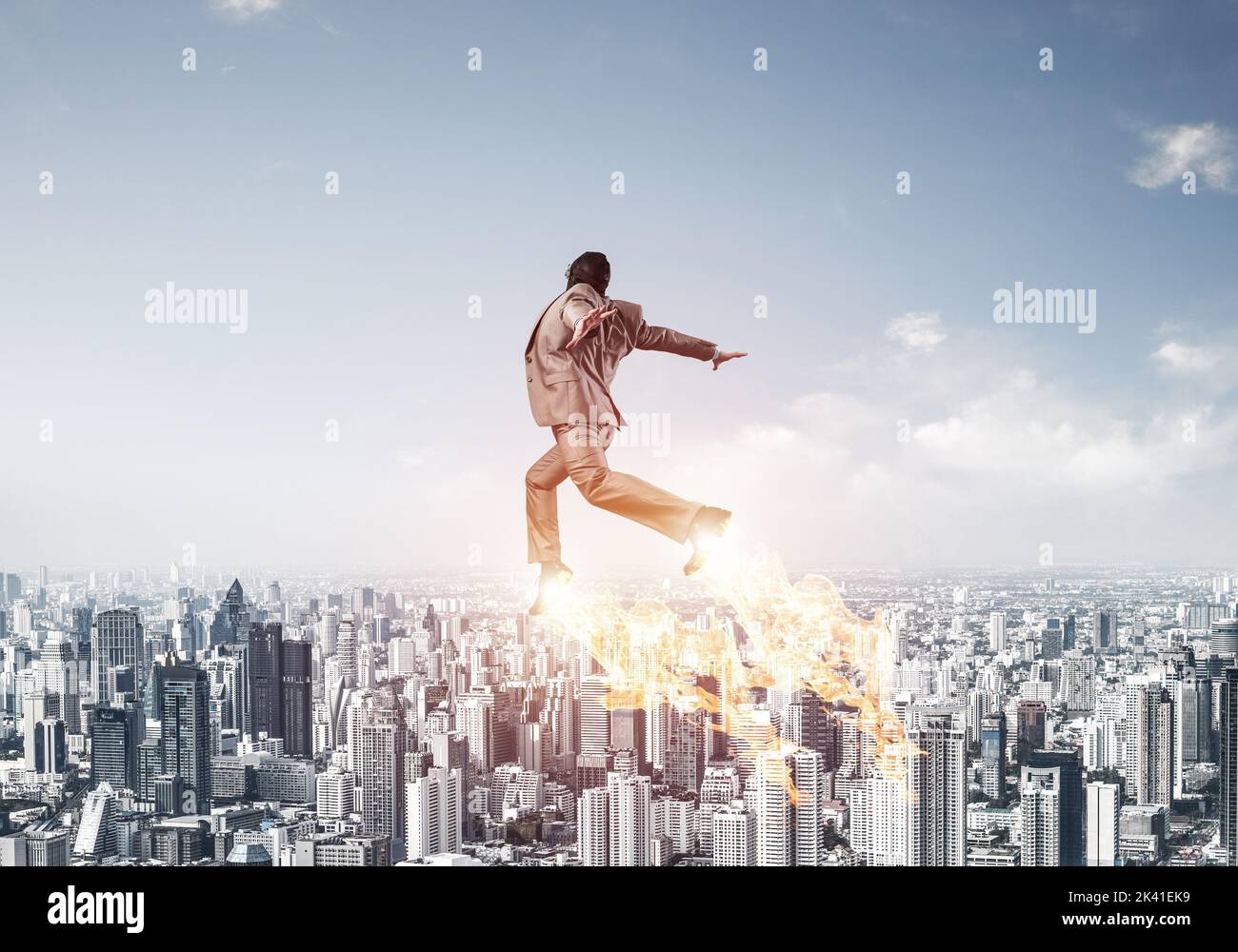 Businessman in suit and aviator hat flying in sky Stock Photo