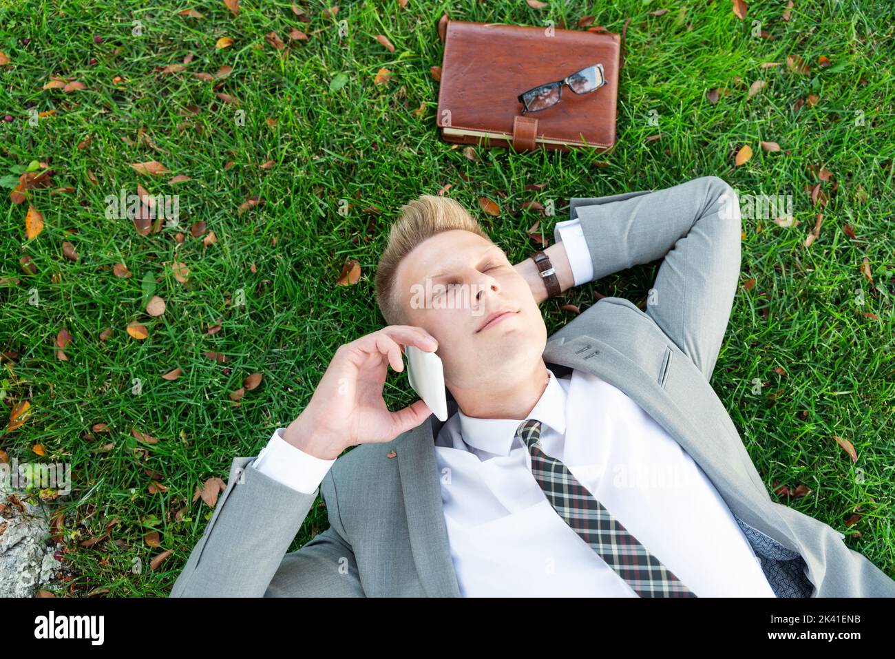 Businessman rests on the grass Stock Photo