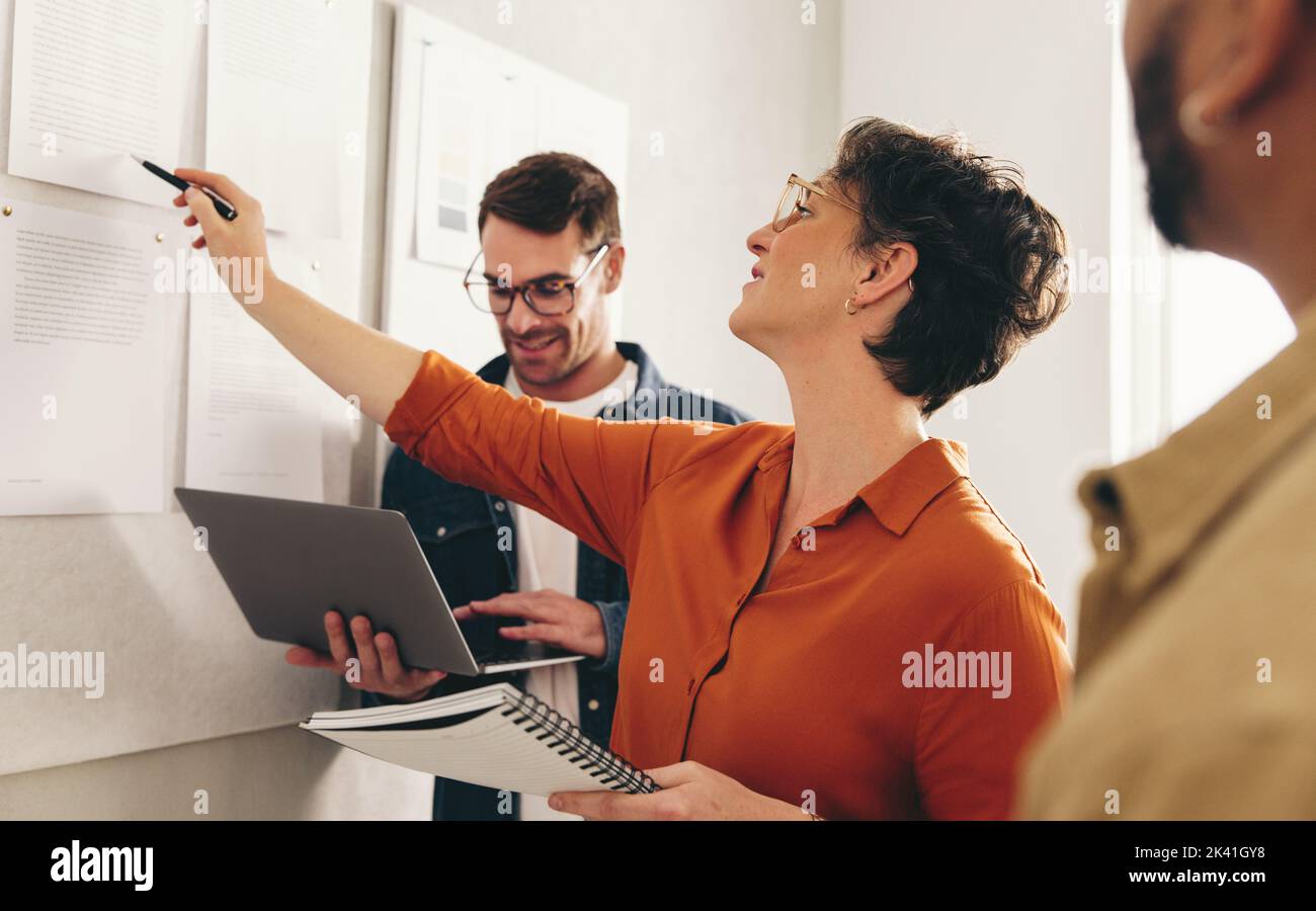 Mature businesswoman discussing some reports with her team during an office meeting. Group of creative businesspeople working on a new strategy in a m Stock Photo