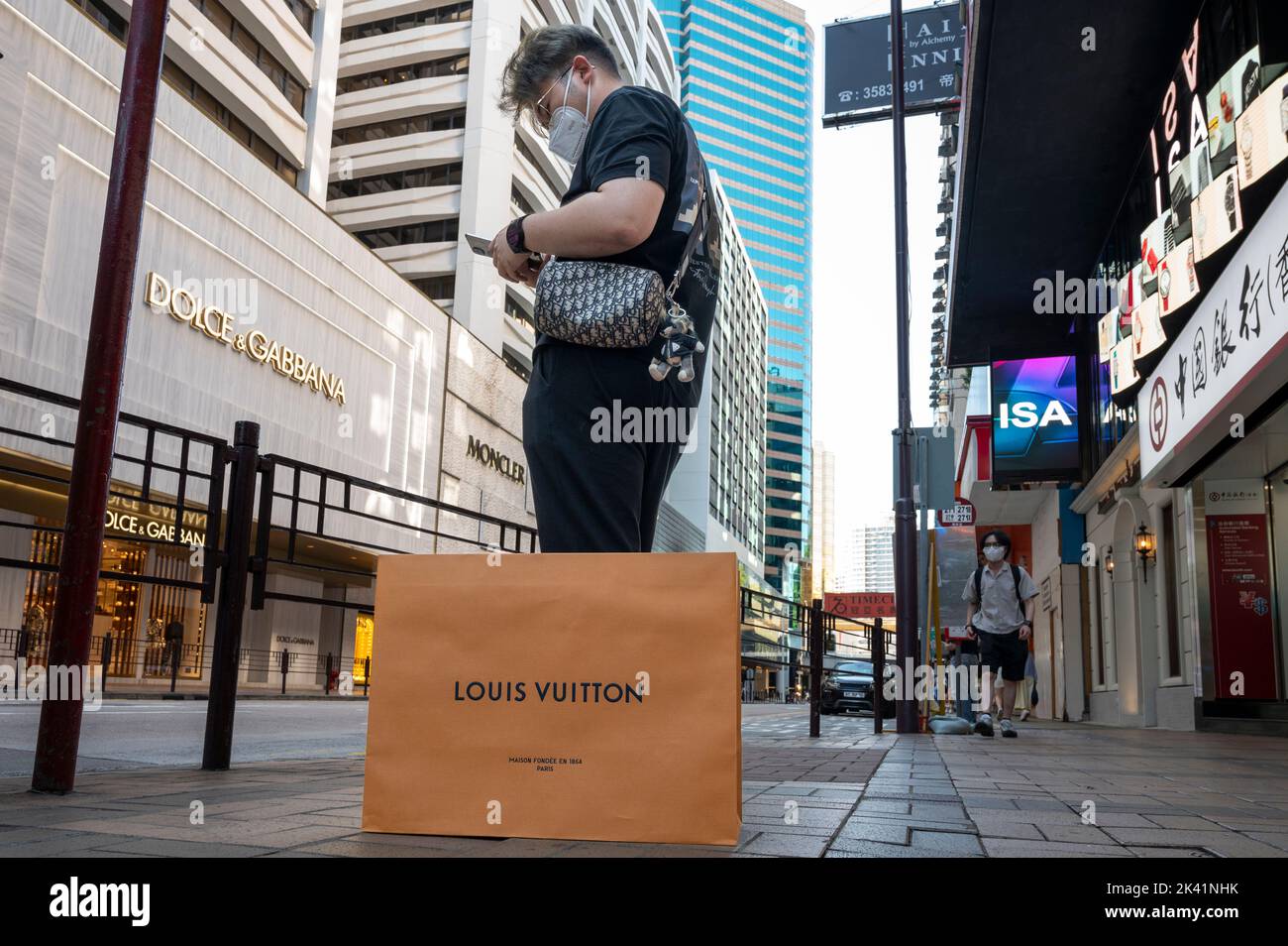 A male customer uses a smartphone next to a Louis Vuitton shopping