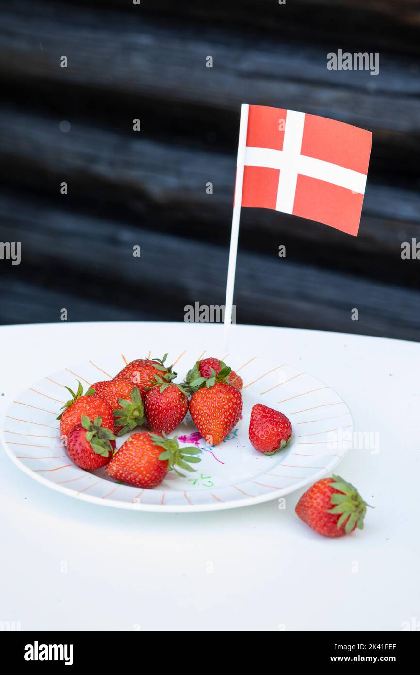 A plate of Danish strawberries with Danish flag outside traditional wooden summer house, Zealand, Denmark Stock Photo