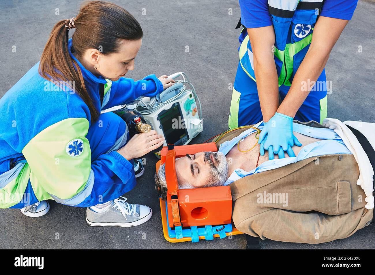 First aid. Cardiopulmonary resuscitation and chest compressions to injured unconscious male from ambulance workers Stock Photo