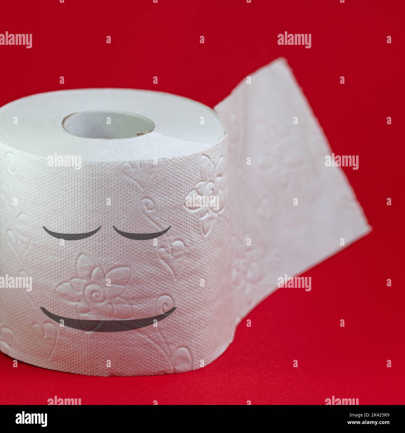 Toilet paper with dreamy face against a red background Stock Photo