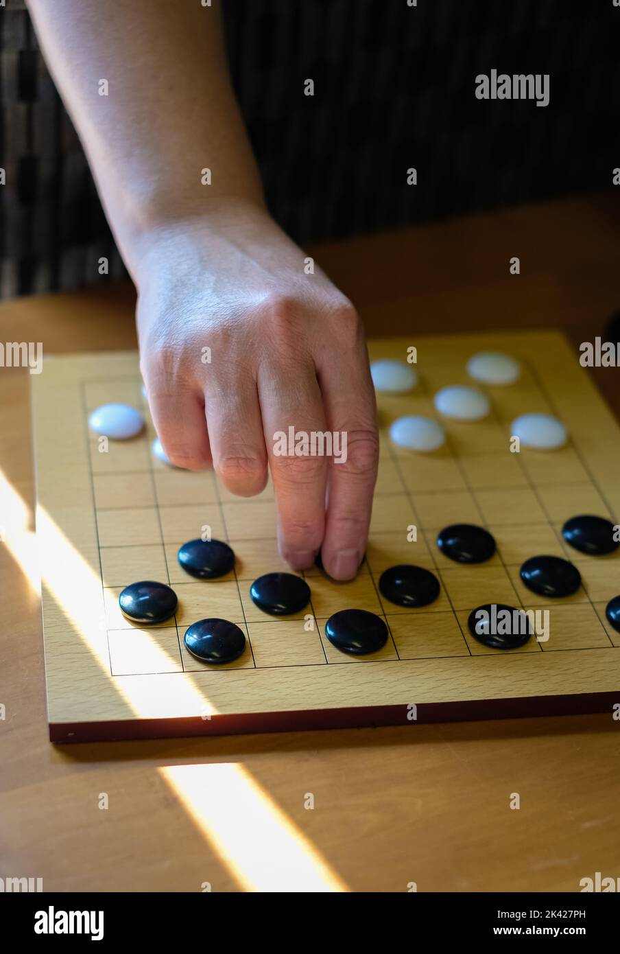 Chinese go game board, close up view of playing black and white stone pieces, Alphago. Hands of woman playing Asian board game. Selective focus Stock Photo