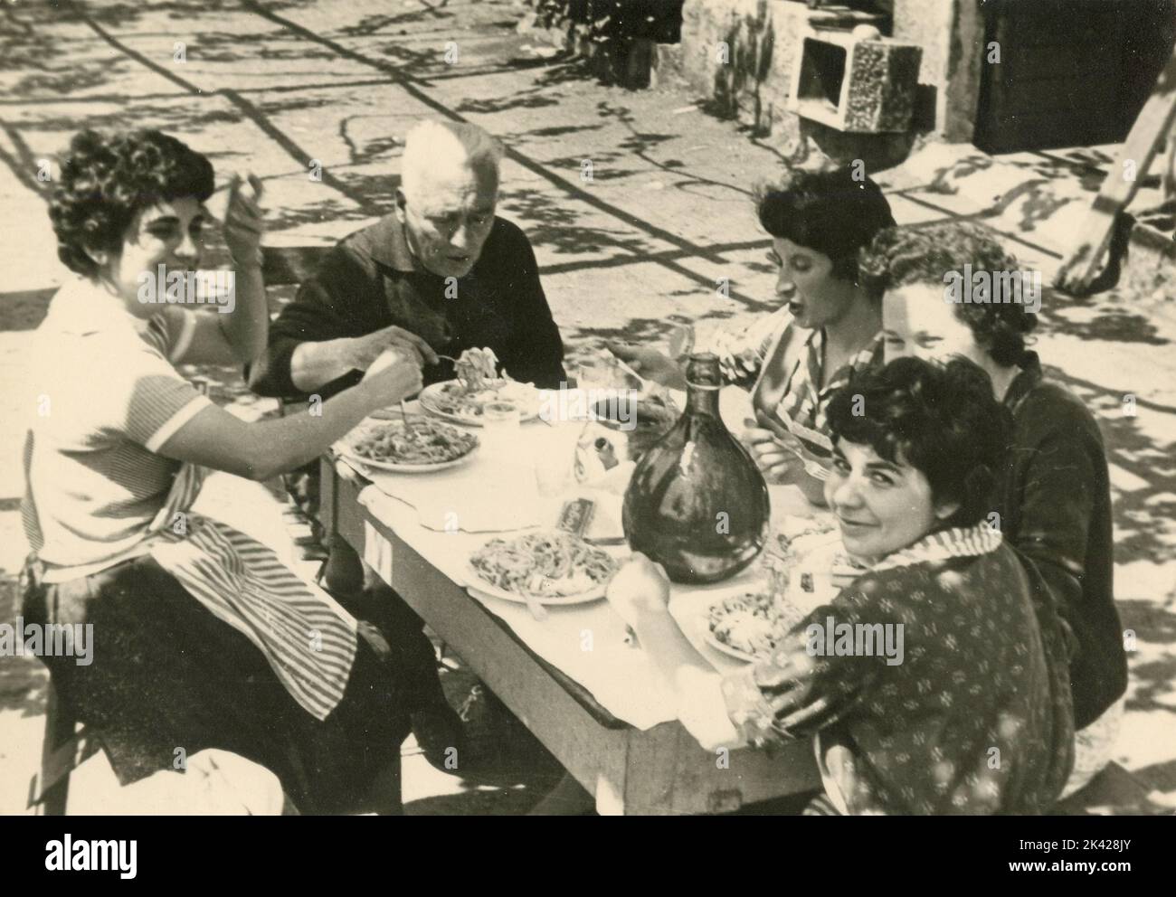 Family eating spaghetti outside in the terrace, Italy 1950s Stock Photo