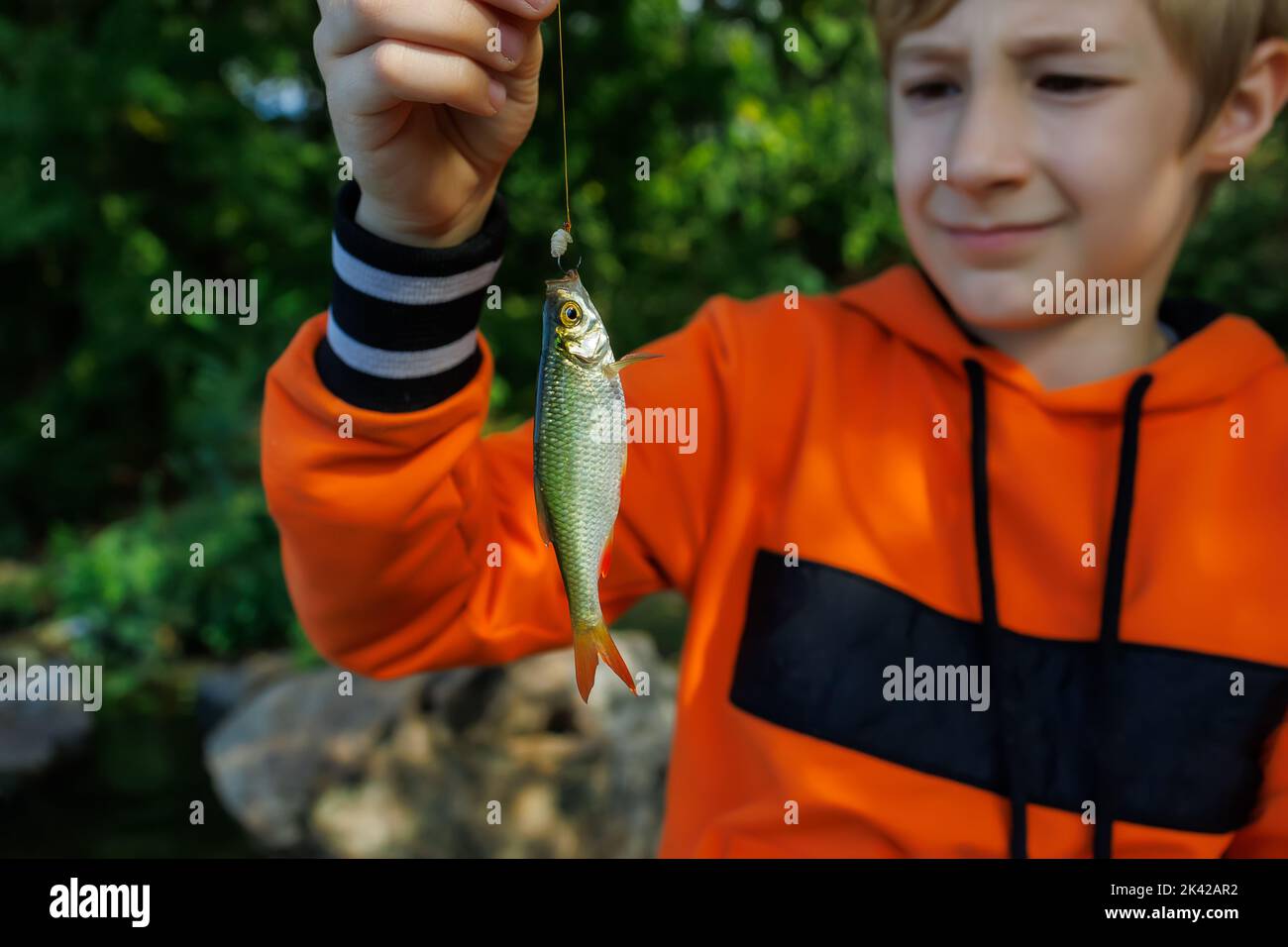 close-up of a small fish that the boy caught. He holds it in front