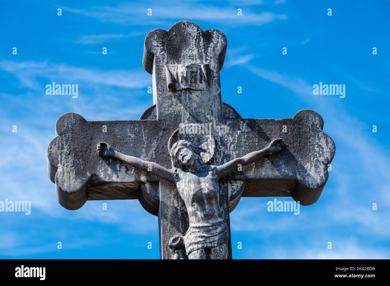 Statue of Christ on the cross against a blue sky in France Stock Photo