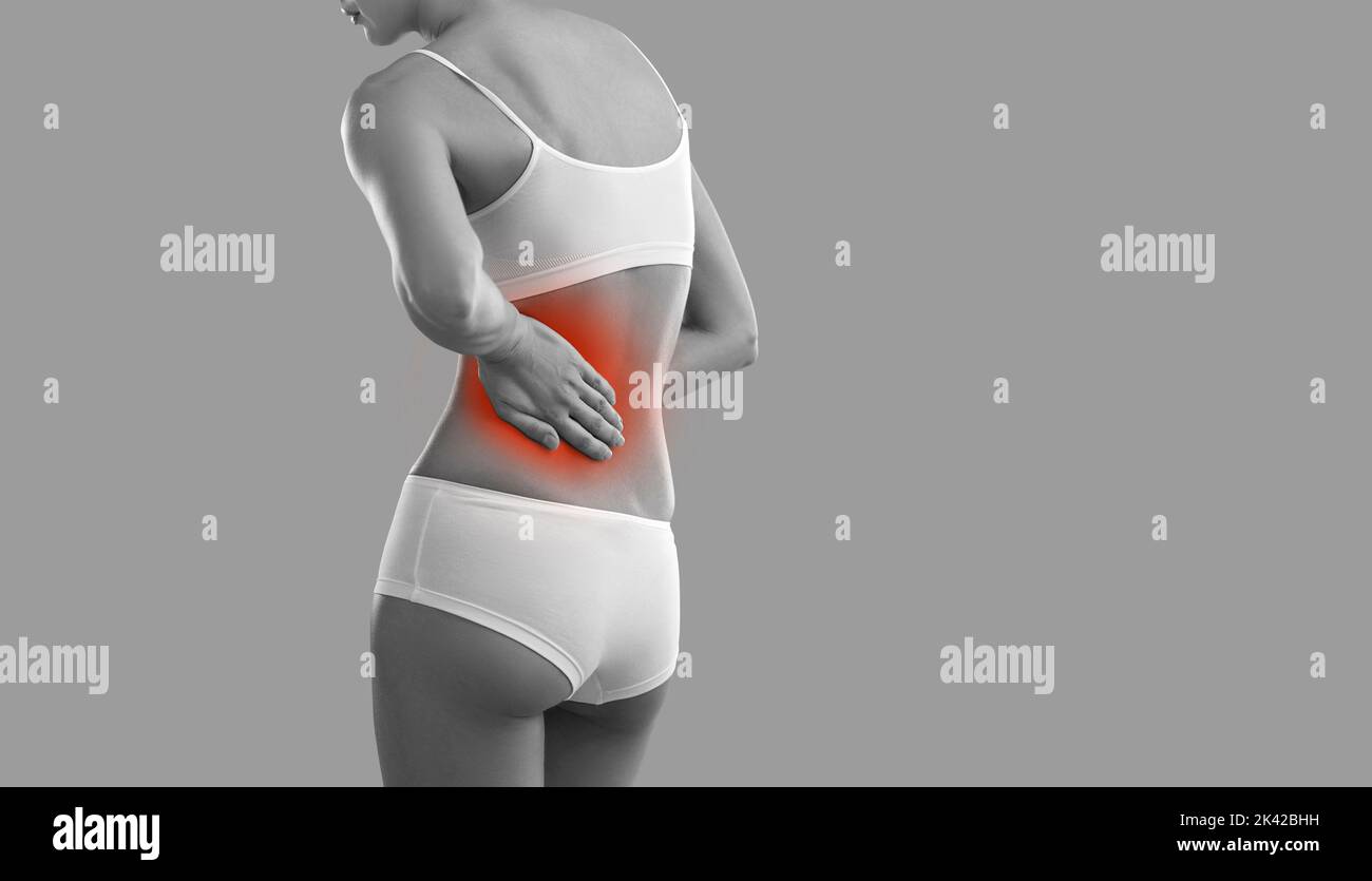Woman suffering from backache or pain in her left side standing on grey banner background Stock Photo