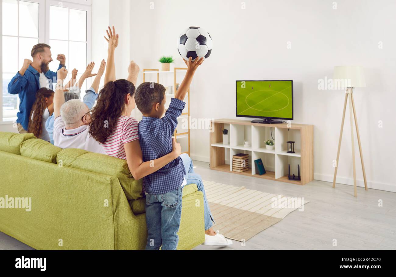 Family together emotionally cheer for national team while watching football match at home. Stock Photo