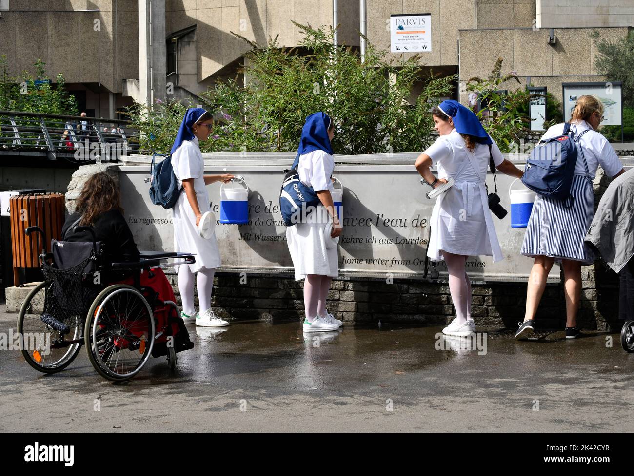 Lourdes, Hautes-Pyrénées, France. Christian pilgrims collecting Lourdes water that flows from the Grotto of Massabielle in the Sanctuary of Our Lady o Stock Photo