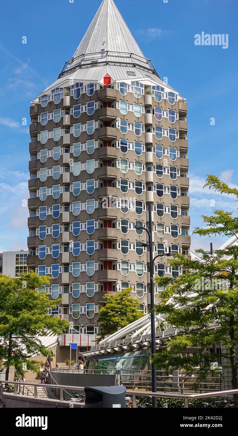 Rotterdam, Netherlands - July 11, 2022: Tall Kolk residential building on Blaak square with its pyramidical roof against blue sky. Some green foliage Stock Photo