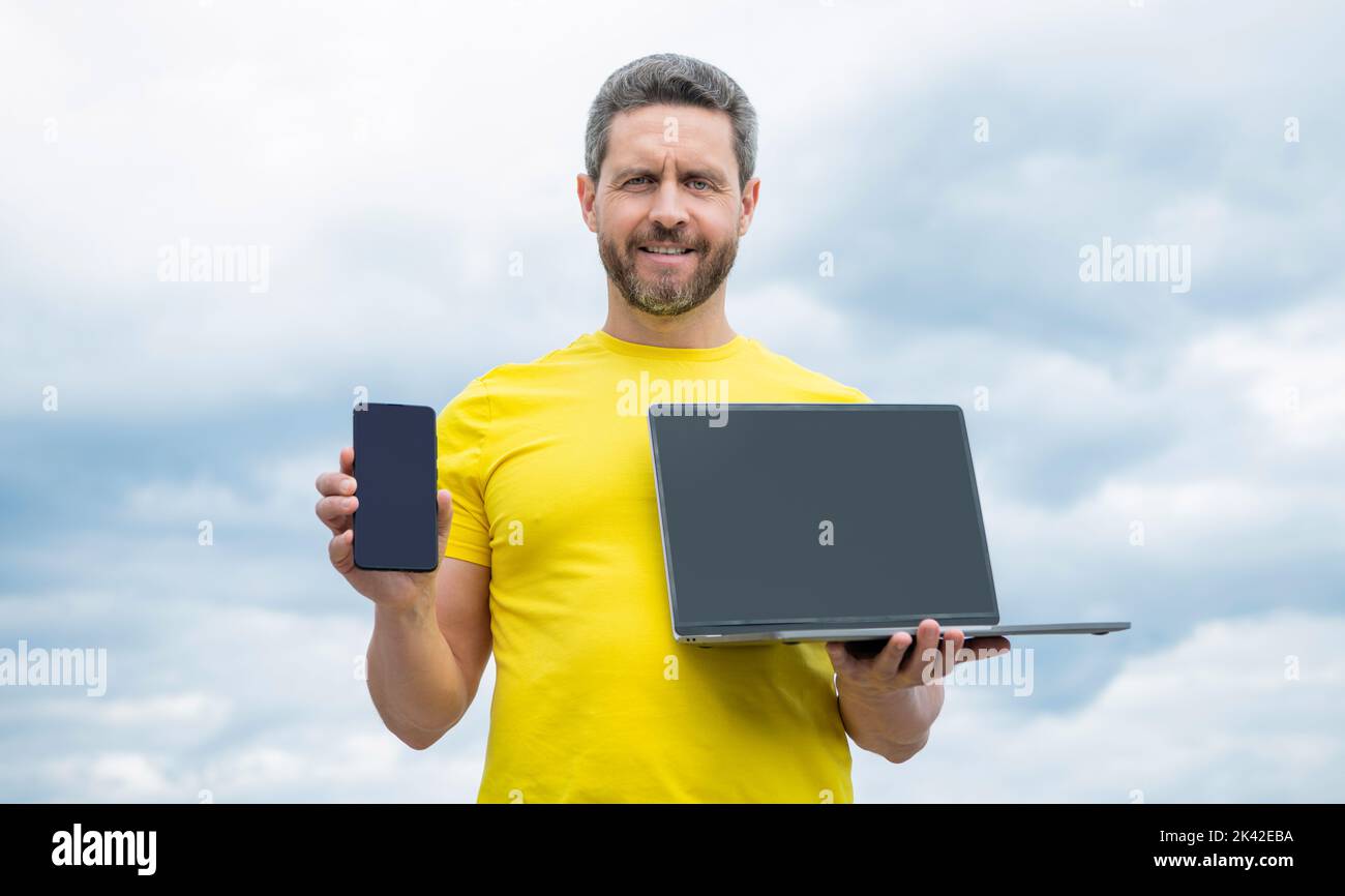 man advertising smartphone and laptop on sky background Stock Photo
