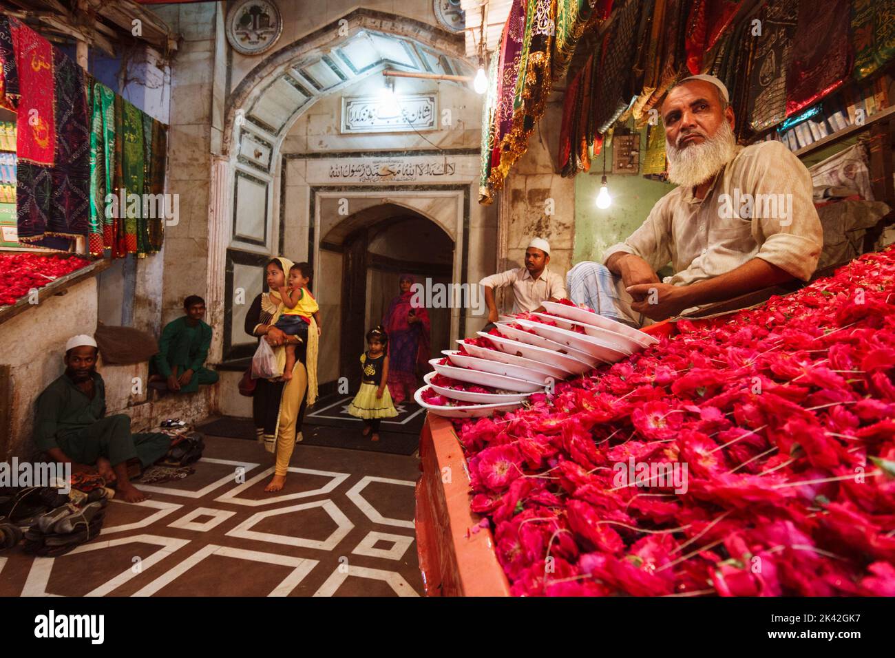 Delhi, India : A vendor seats at a rose petals stall at the entrance of Nizamuddin Dargah. The bazaars around offer all kinds of attars (perfumes) and Stock Photo