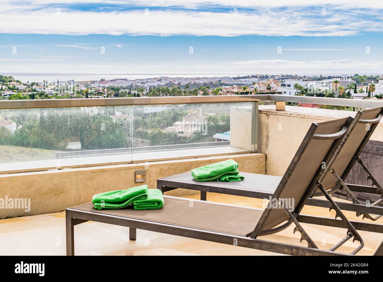 a view overlooking the Mediterranean coastline of the Costa Del Sol From the terrace of a luxury apartment complete with deck chairs close up Stock Photo