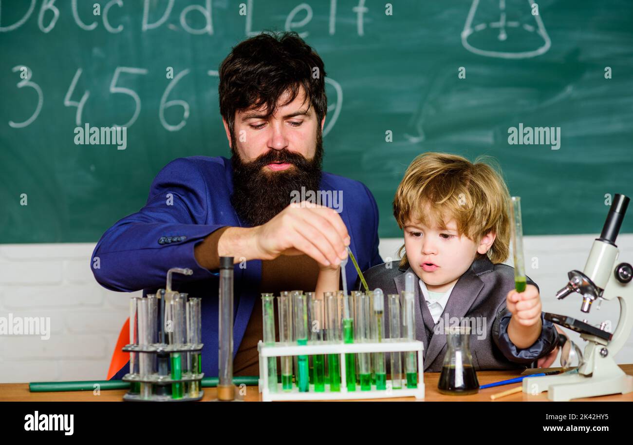 Laboratory test tubes and flasks with colored liquids bearded man teacher with little boy. Chemistry beaker experiment. father and son child at school Stock Photo