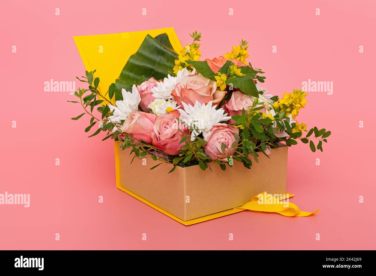 Original flower arrangement in a yellow gift box, on a pink background Stock Photo