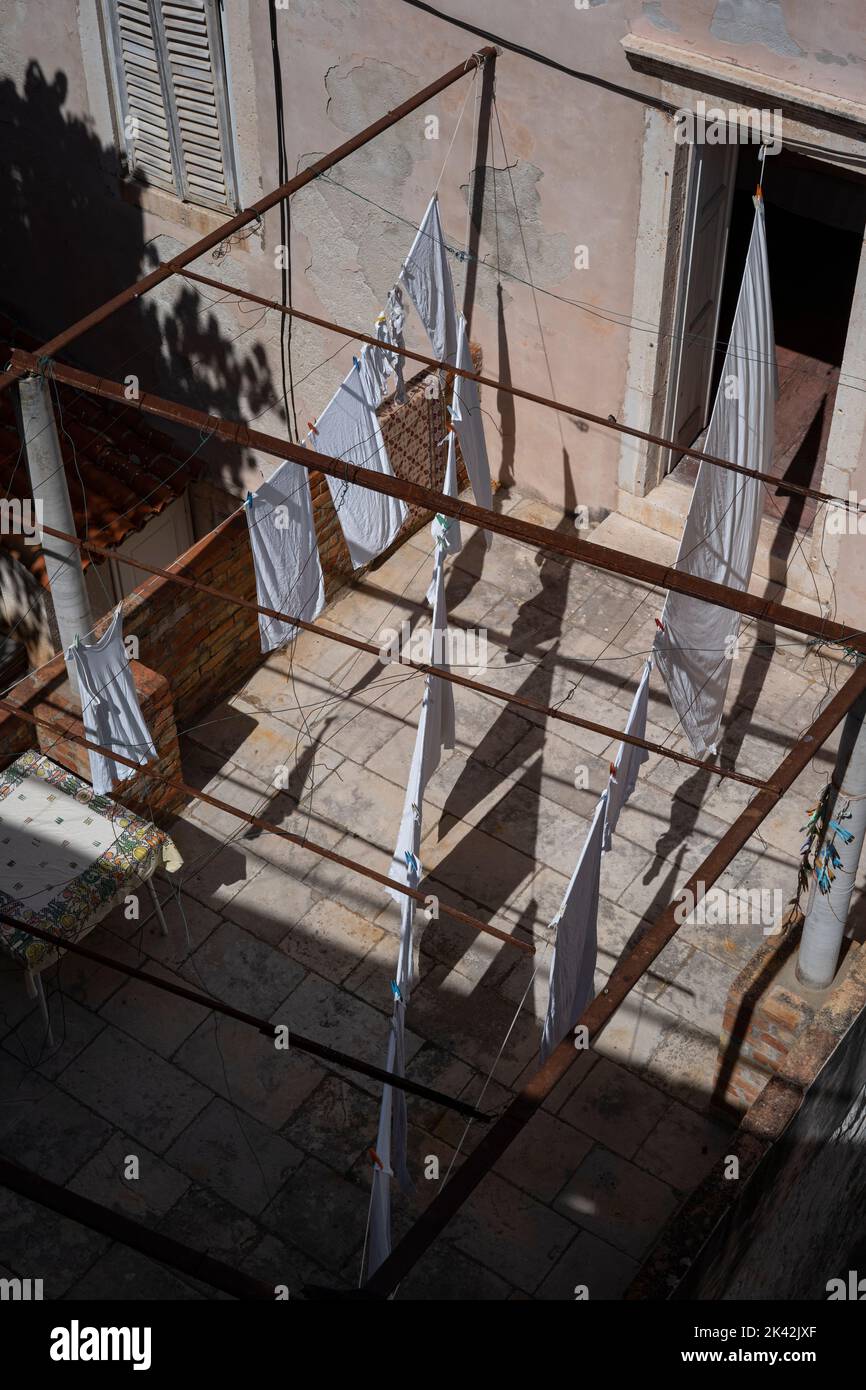 white bed sheets and laundry drying on a sunny patio seen from above Stock Photo