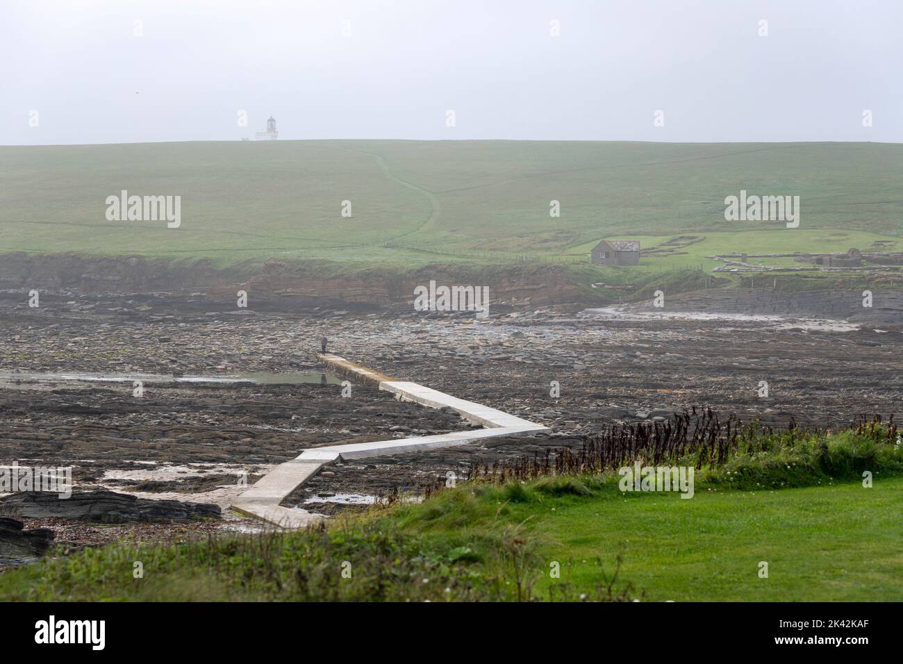 Tourists walking along the concrete pathway to the island Brough of Birsay, The Mainland of Orkney, Scotland, UK Stock Photo