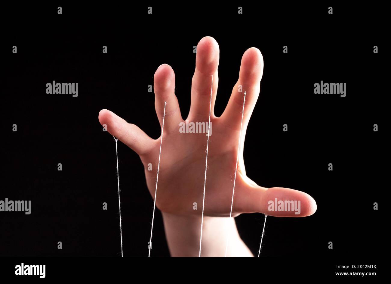 Manipulation, authority concept. Hand with strings controlling, manipulating smth abstract. Stock Photo