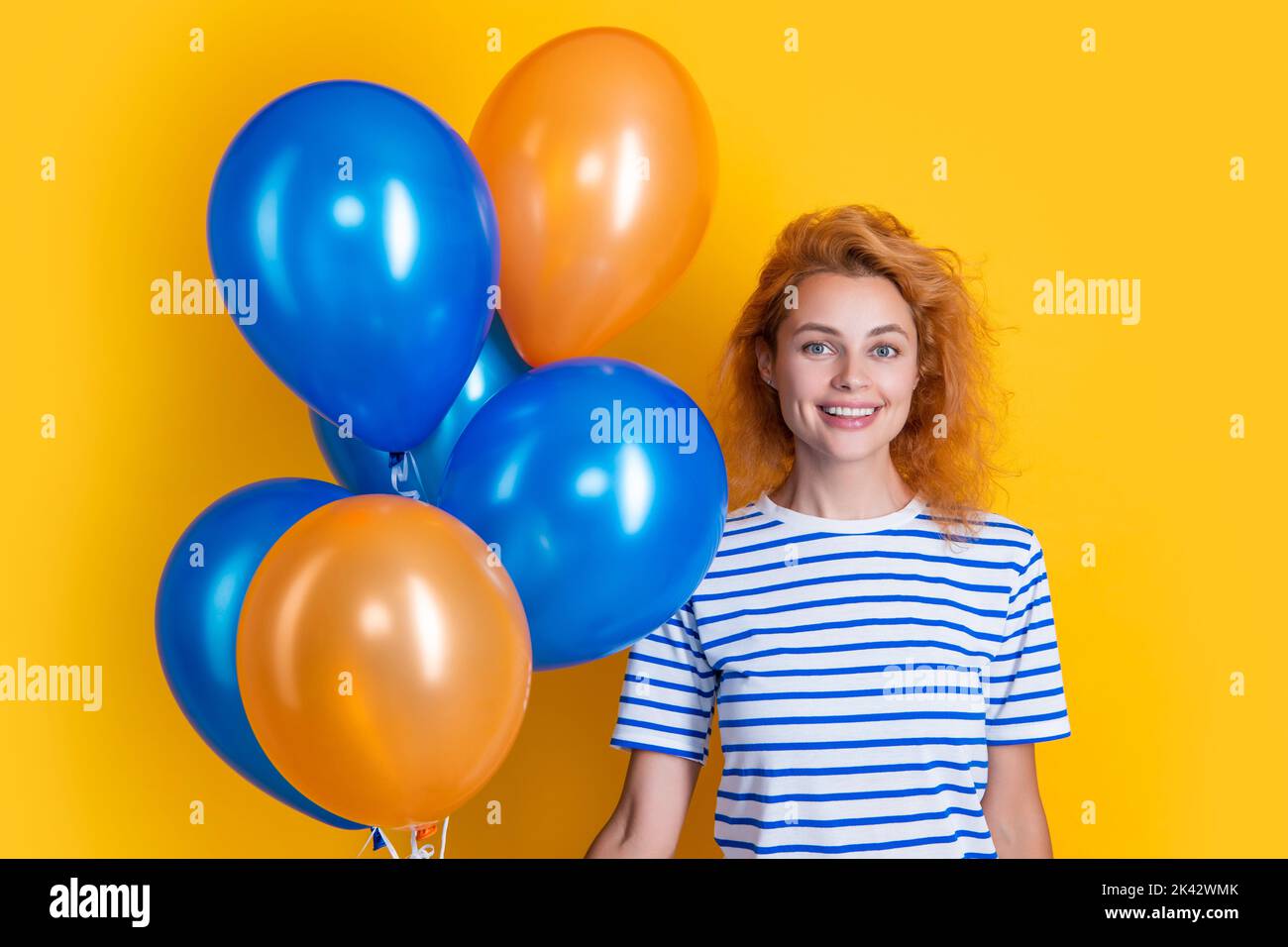 happy woman hold party balloons in studio. woman with balloon for party isolated on yellow Stock Photo