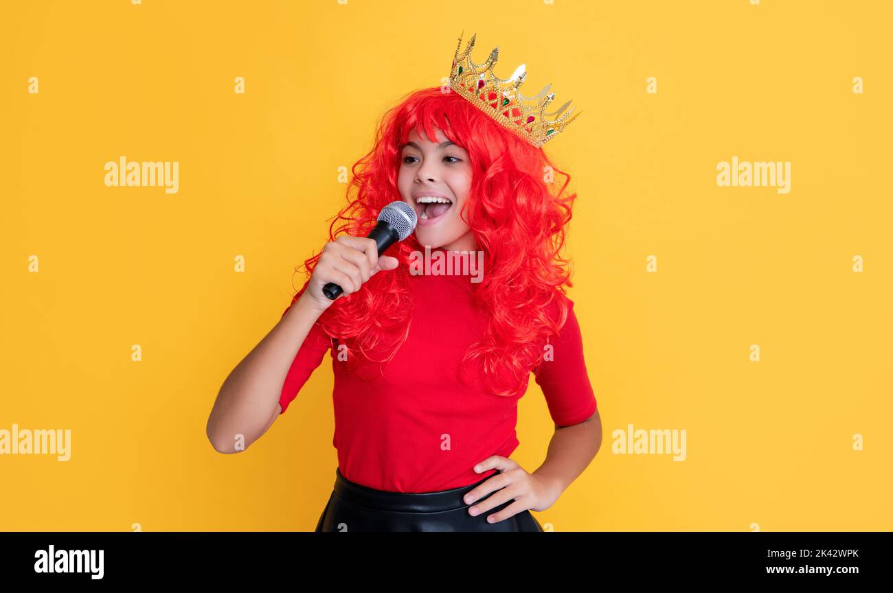 smiling kid in crown with microphone on yellow background Stock Photo