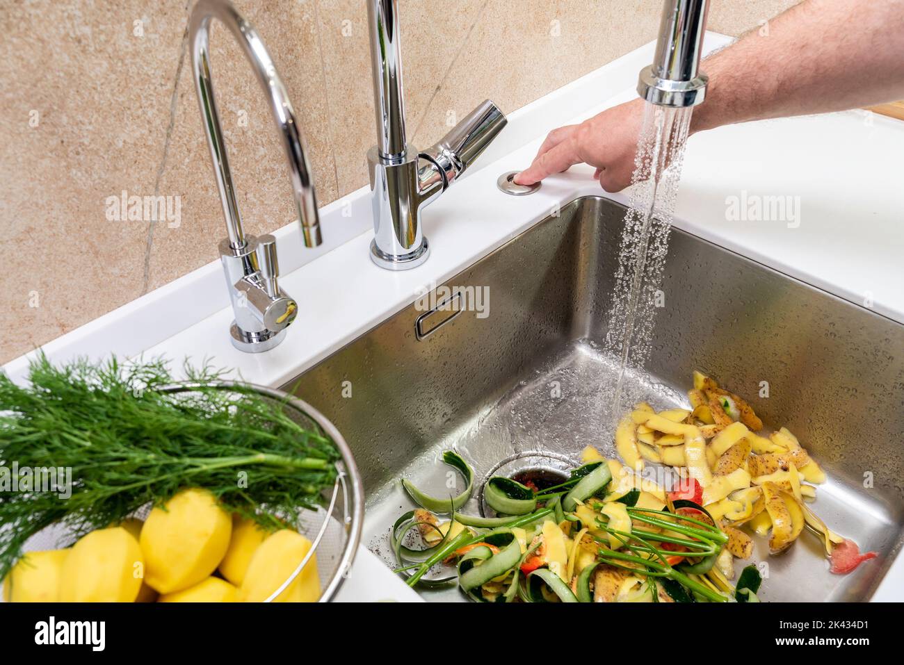 Turning on a disposer in a modern kitchen to remove food waste Stock Photo