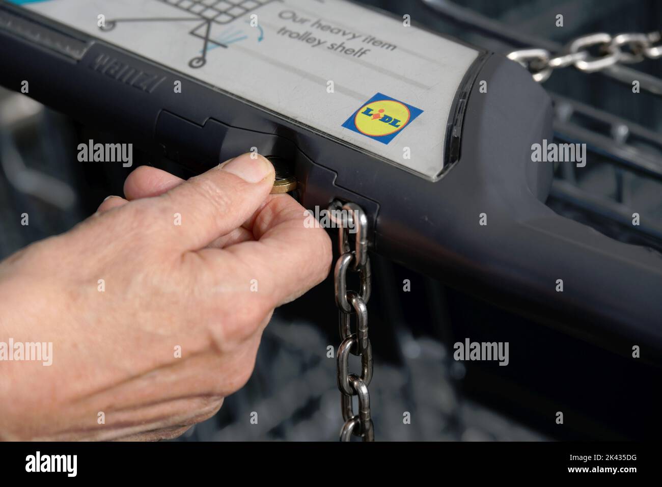 Inserting coin in shopping trolley to unlock so it can be used. Part of trolley theft protection. Stock Photo