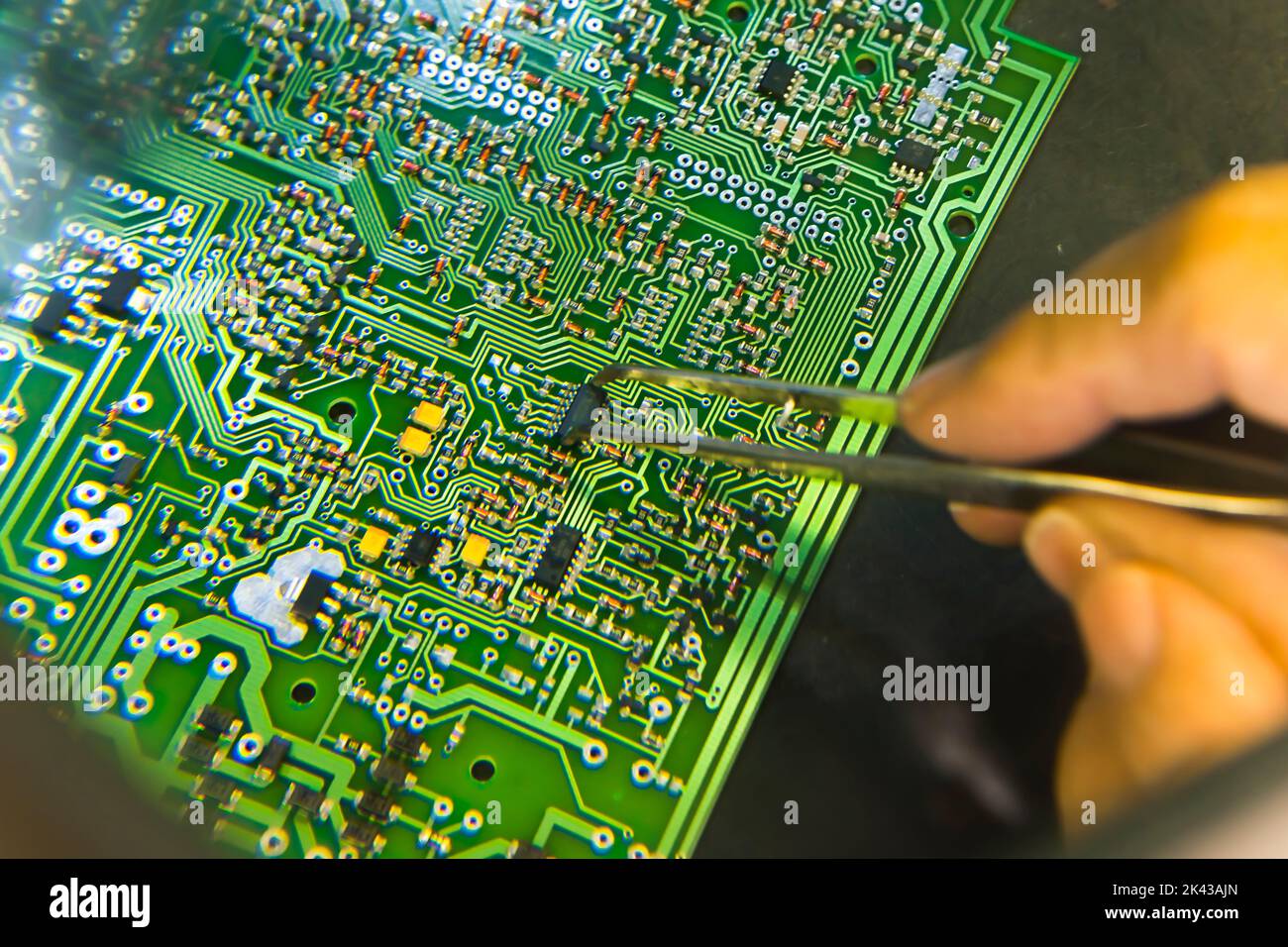 The man hand of the technician assembling manualy electronic components and microcircuits on printing circuit board with printed multi wire connections. Electronics Manufacturing Services. High quality photo Stock Photo