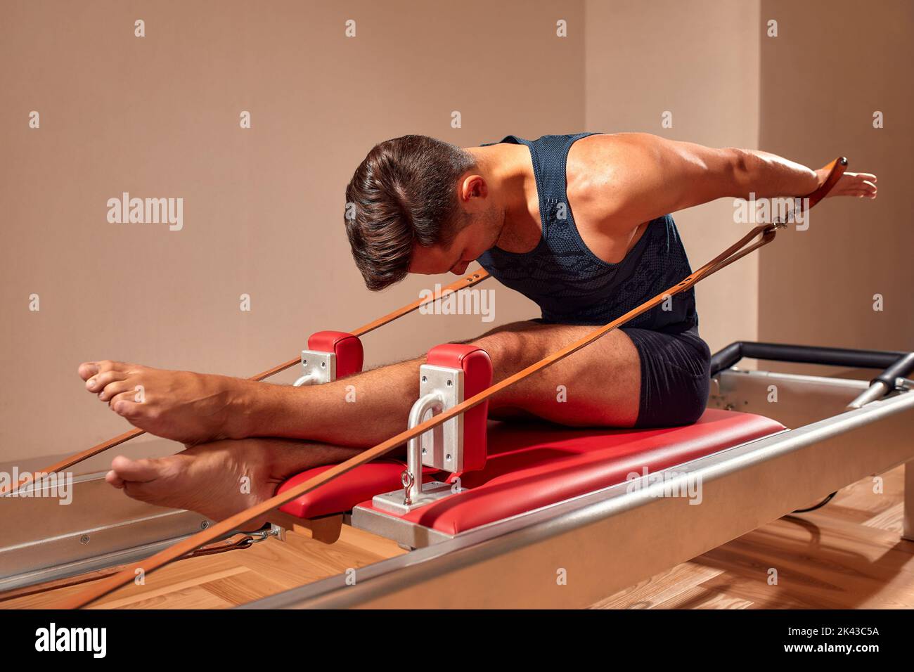 Side view of barefoot male athlete lying on pilates reformer and
