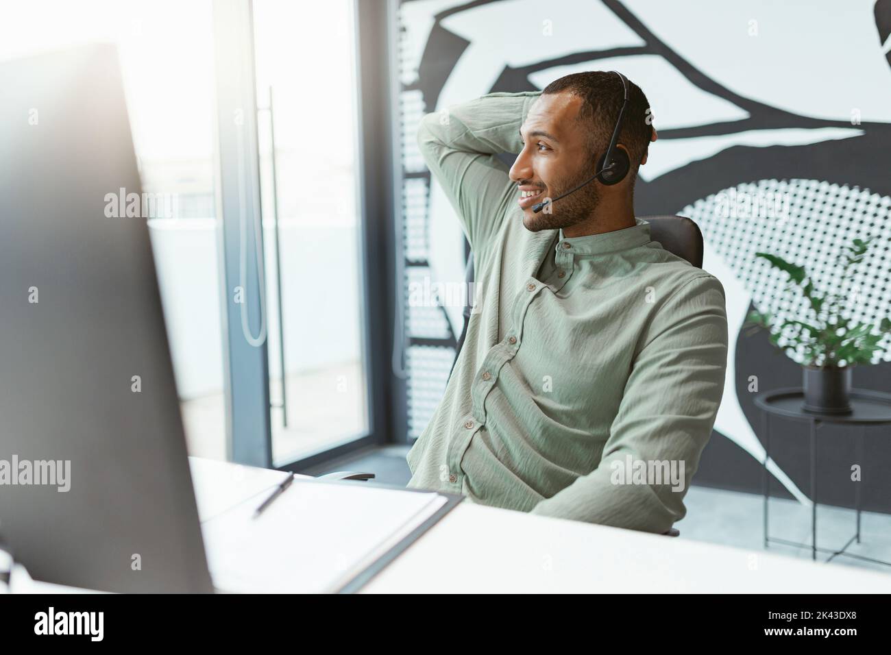 Smiling african businessman working on computer while sitting in modern ...